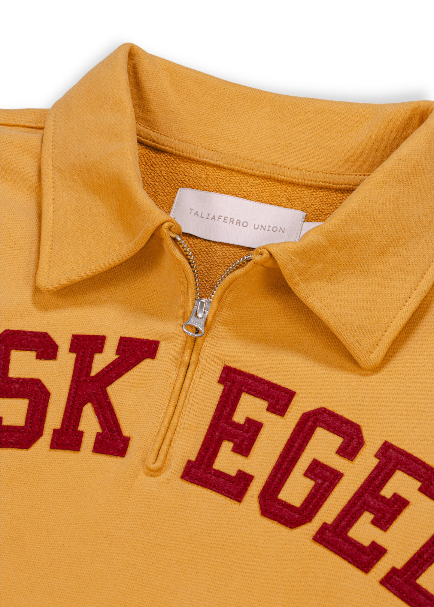 Close up detail shot of old gold Tuskegee University sweatshirt featuring bold "TUSKEGEE" felt appliqué lettering across chest. Vintage HBCU apparel