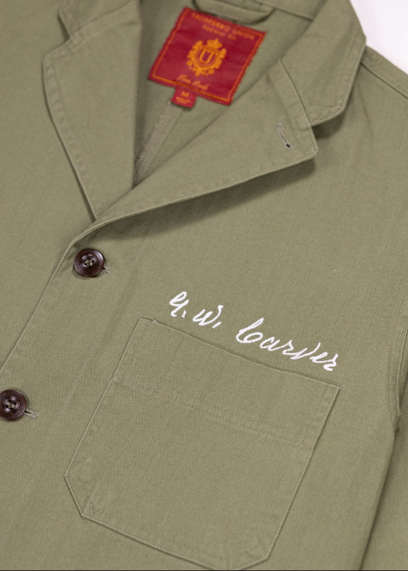 Closeup shot of Olive Chore coat featuring the signature of George Washington Carver