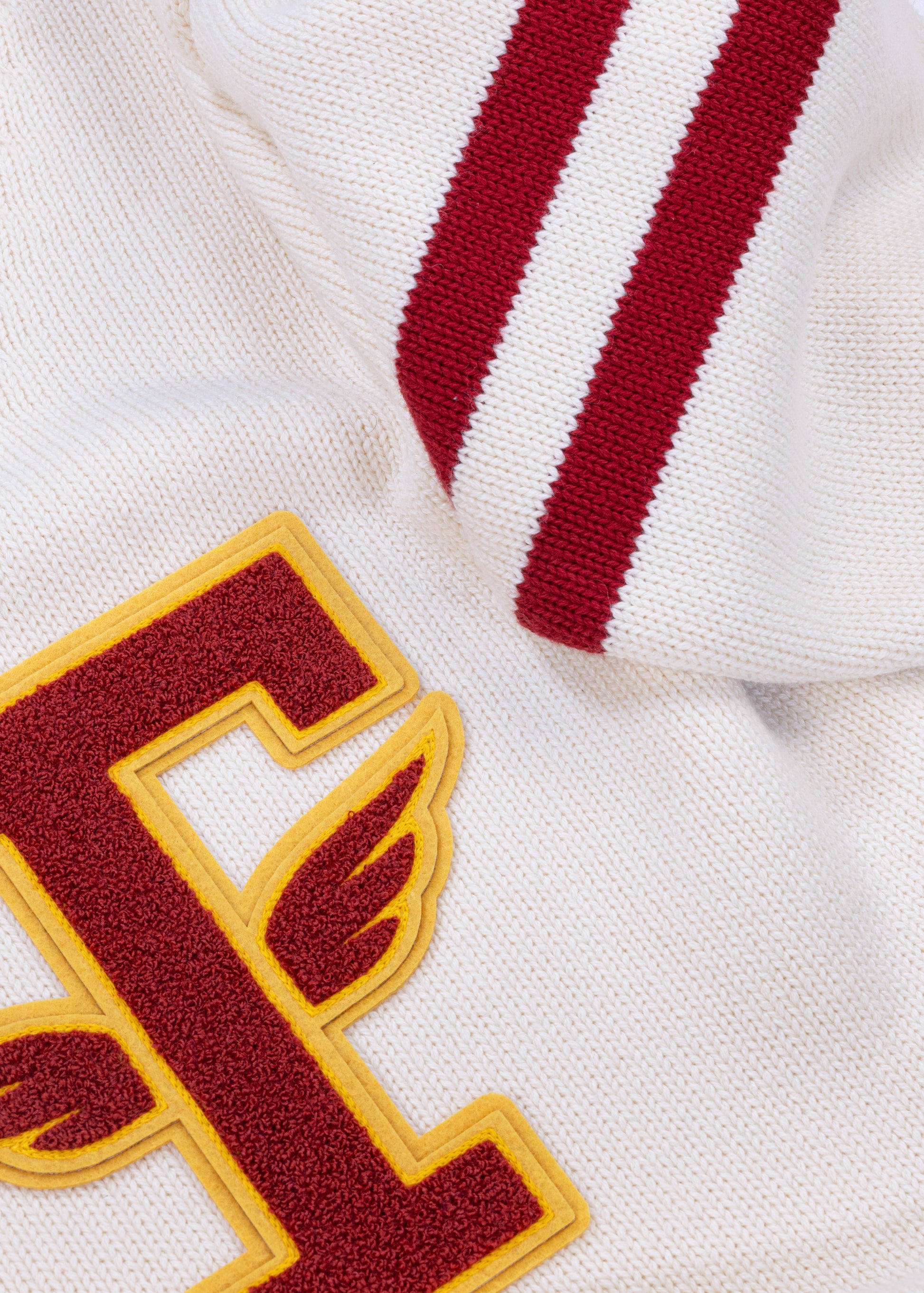 Close up detail shot of Tuskegee University v-neck pullover sweater, vintage inspired by Tuskegee University student yearbooks, wool-cotton blend, HBCU apparel. Featuring Chenille T patch and knitted stripes on sleeves