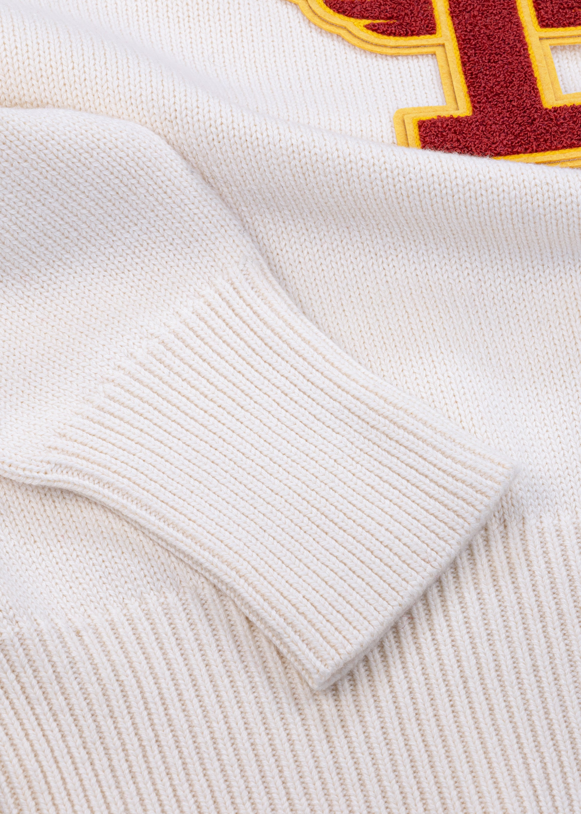 Close up detail shot of Tuskegee University v-neck pullover sweater, vintage inspired by Tuskegee University student yearbooks, wool-cotton blend, HBCU apparel. Featuring Chenille T patch with ribbed cuffs