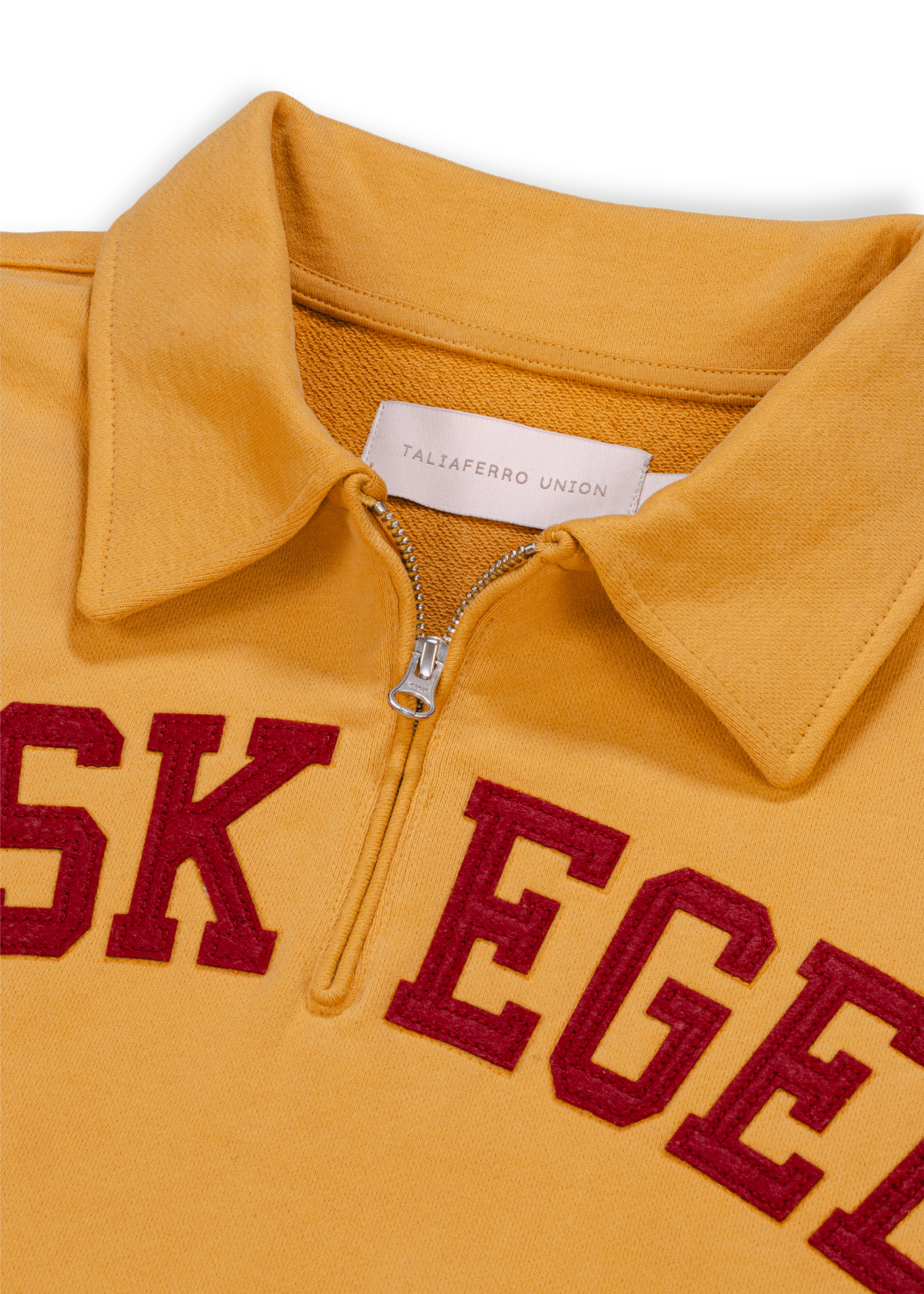 Close up detail shot of old gold Tuskegee University sweatshirt featuring bold "TUSKEGEE" felt appliqué lettering across chest. Vintage HBCU apparel 
